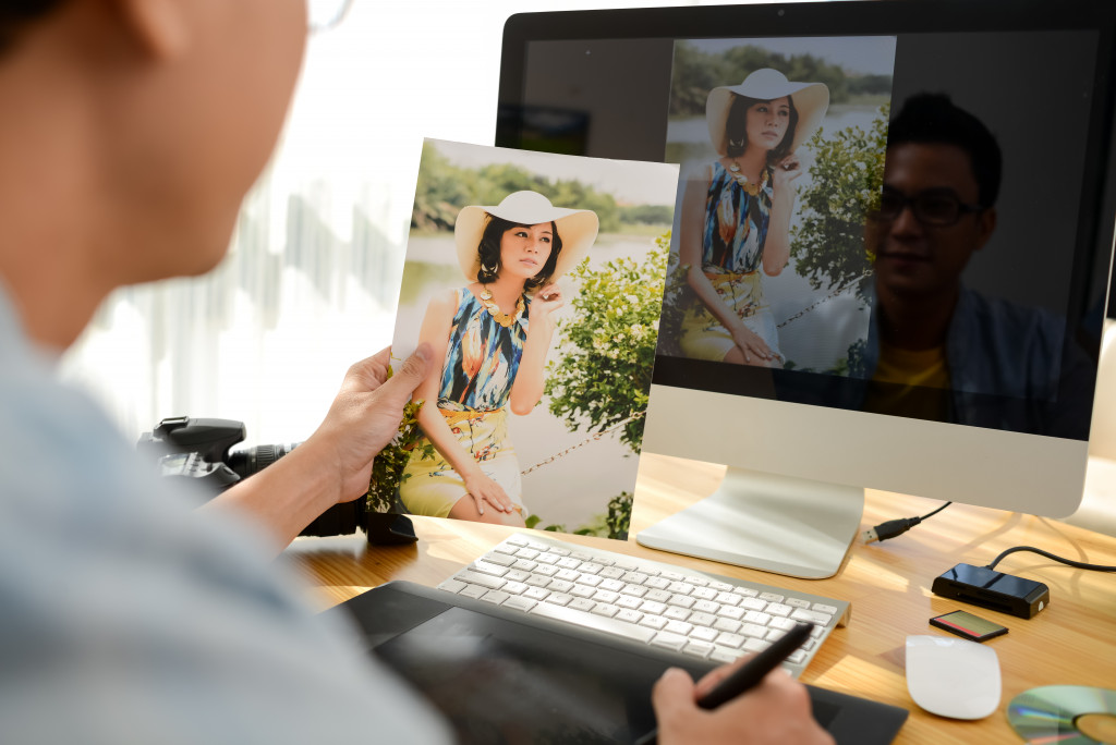 man holding a photograph of a woman and editing it on the computer