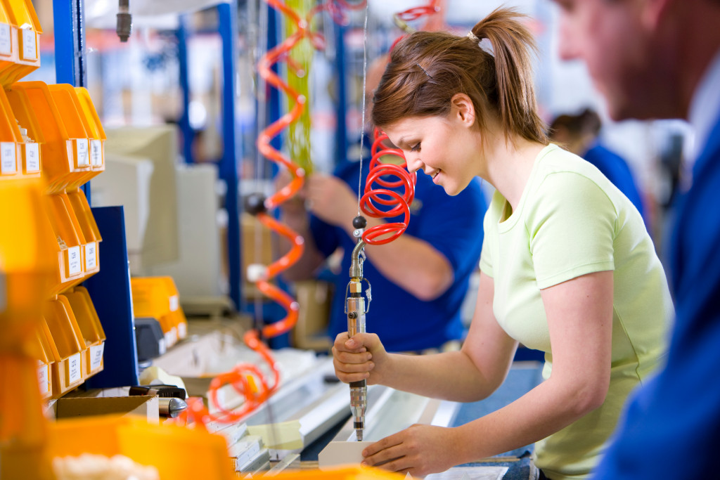 young female worker in casuals operating machinery