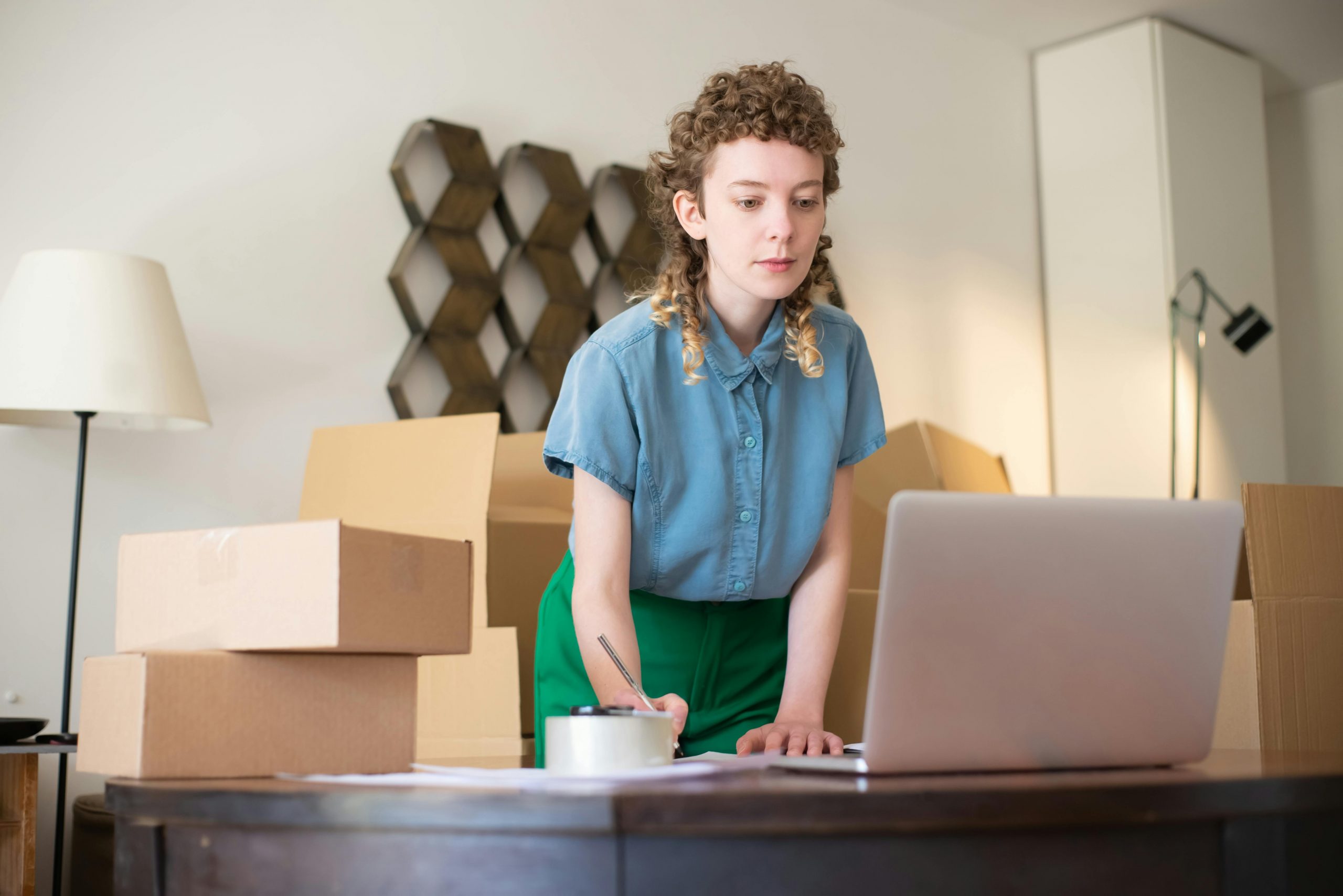 online seller writing in a notebook while referencing her laptop screen
